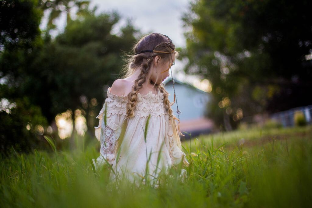 young girl standing outside wearing a boho-inspired headband modeling "Boho Side Braids" hairstyle