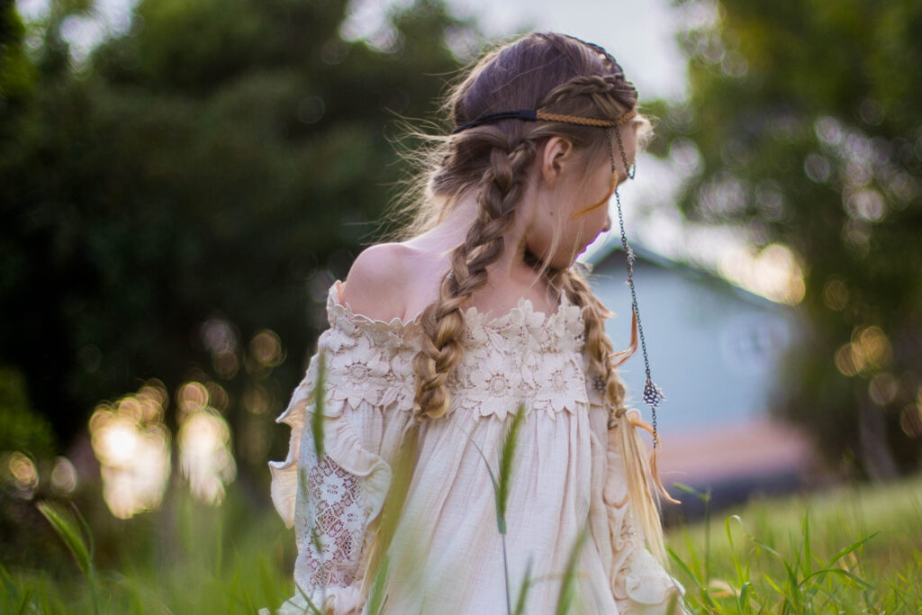 young girl standing outside wearing a boho-inspired headband modeling "Boho Side Braids" hairstyle