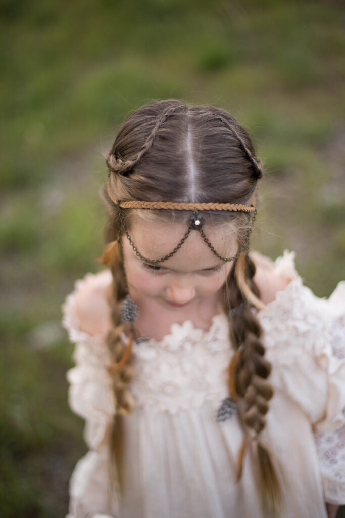 Top view of young girl standing outside wearing a boho-inspired headband modeling "Boho Side Braids" hairstyle