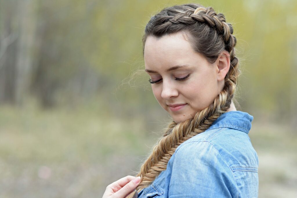 Side profile girl wearing a blue shirt standing outside modeling "Double Dutch Fishtails" hairstyle