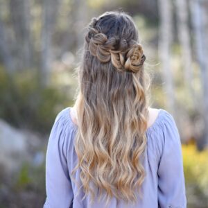 Back view of girl standing outside in the wooded area modeling the "Lace Pull-Thru Rosette Bun" hairstyle