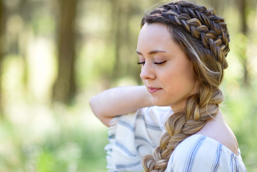 Profile view of a young girl with long hair standing outside modeling "Double Dutch Side Braid" hairstyle