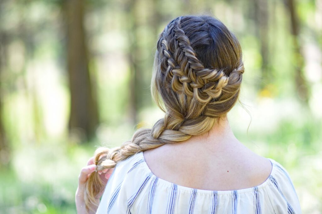 Back view of a young girl with long hair with a striped shirt standing outside modeling "Double Dutch Side Braid" hairstyle