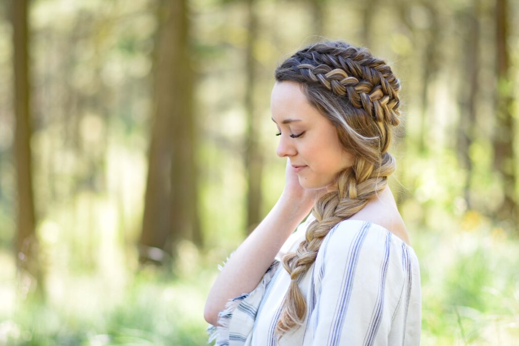 Profile view of a young girl with long hair standing outside modeling "Double Dutch Side Braid" hairstyle