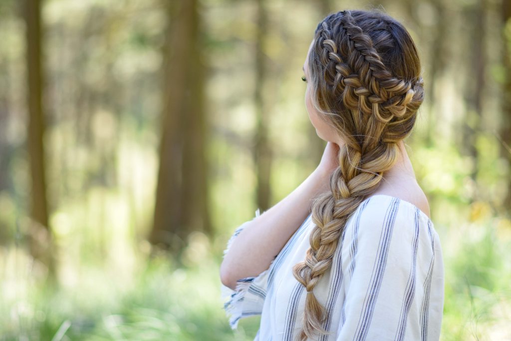 Side view of a young girl with long hair with a striped shirt standing outside modeling "Double Dutch Side Braid" hairstyle