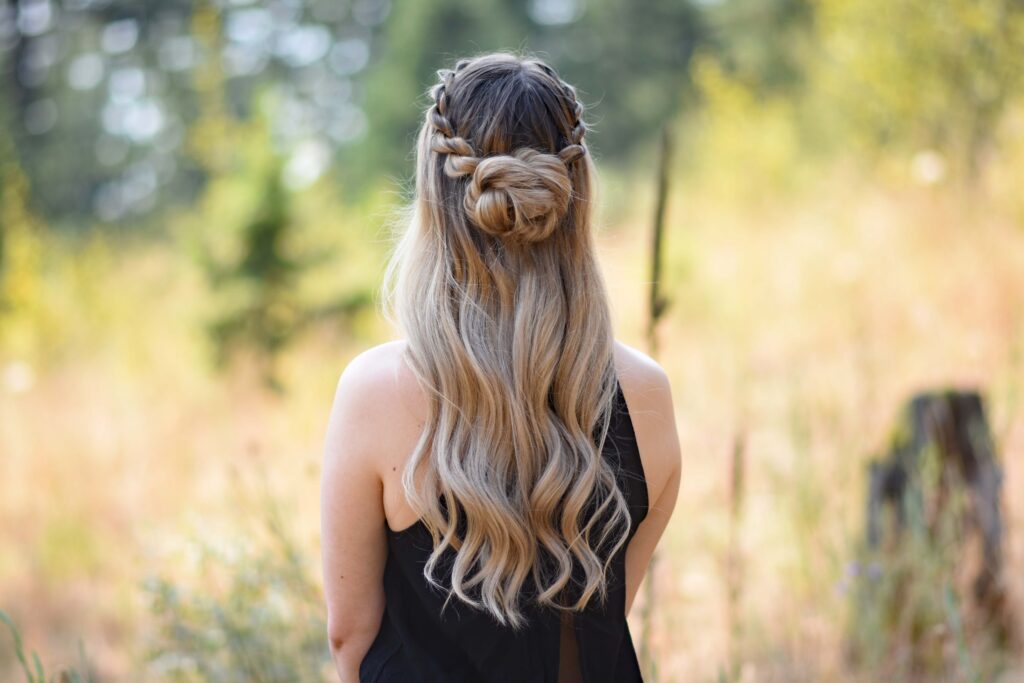 Back view of a young girl wearing a black shirt standing in the meadow modeling "Half-Up Rope Twist Bun" hairstyle