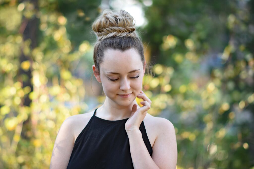 Portrait view of a young girl wearing a black shirt standing in the meadow modeling "Twisted Dutch Braid Ponytail" hairstyle