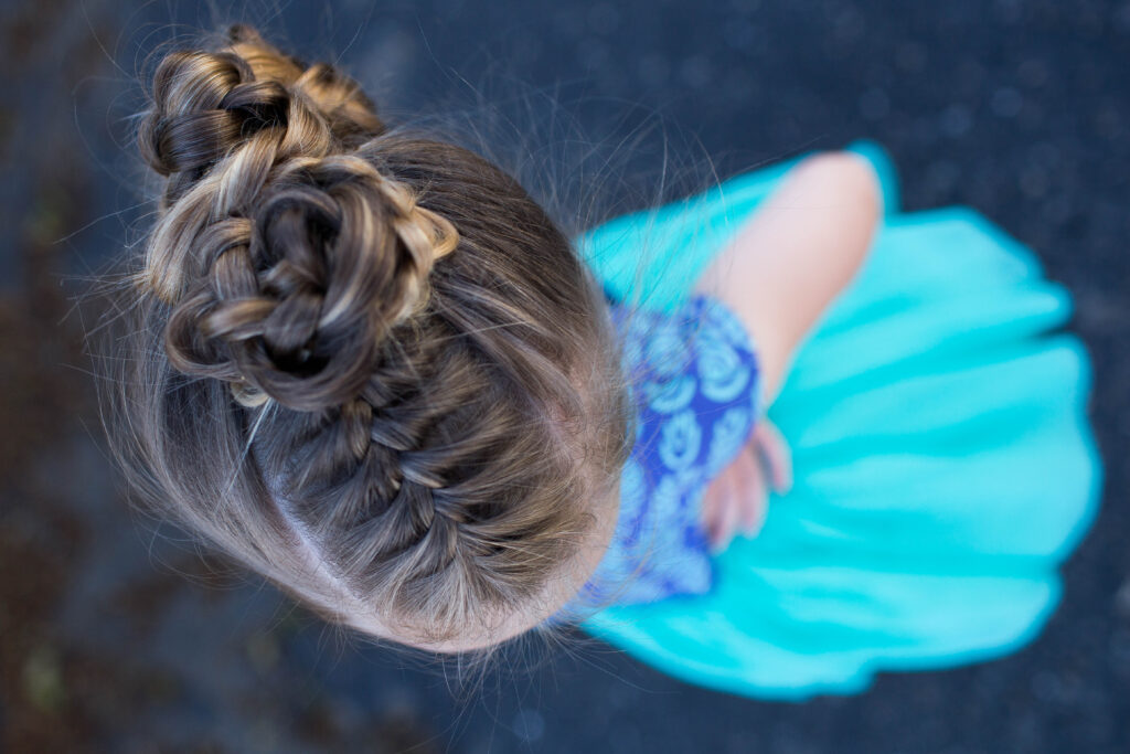 Top view of a little girl with long hair standing outside modeling "Triple Bun Updo" hairstyle