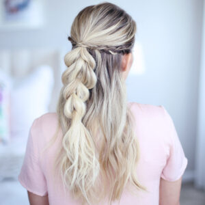 Back view of young woman standing in her room wearing pink shirt modeling "4-in-1 Pull Thru Braid" Hairstyle