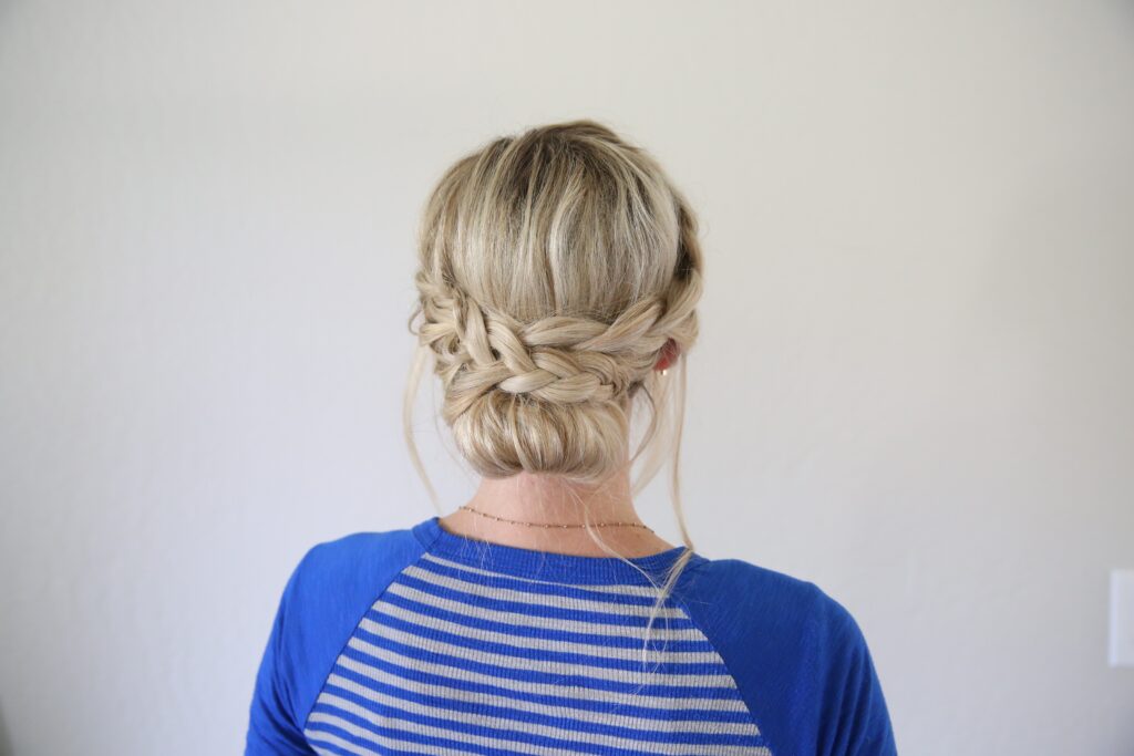 Back view of woman standing in front of a white background with a blue shirt modeling "French Lace Updo" hairstyle