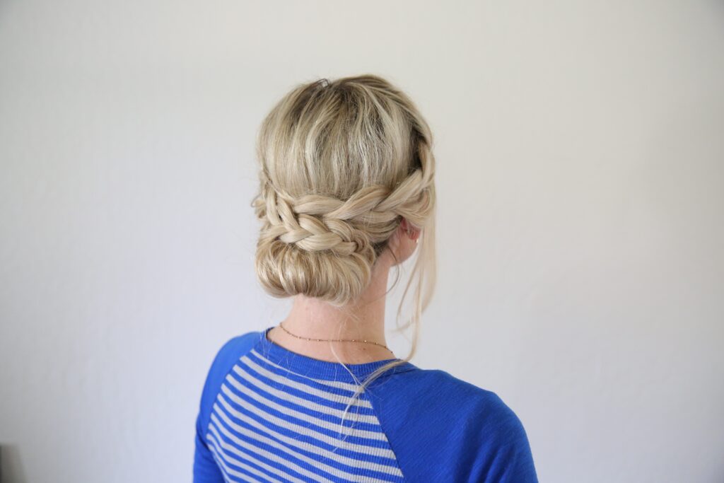 Side view of woman standing in front of a white background with a blue shirt modeling "French Lace Updo" hairstyle