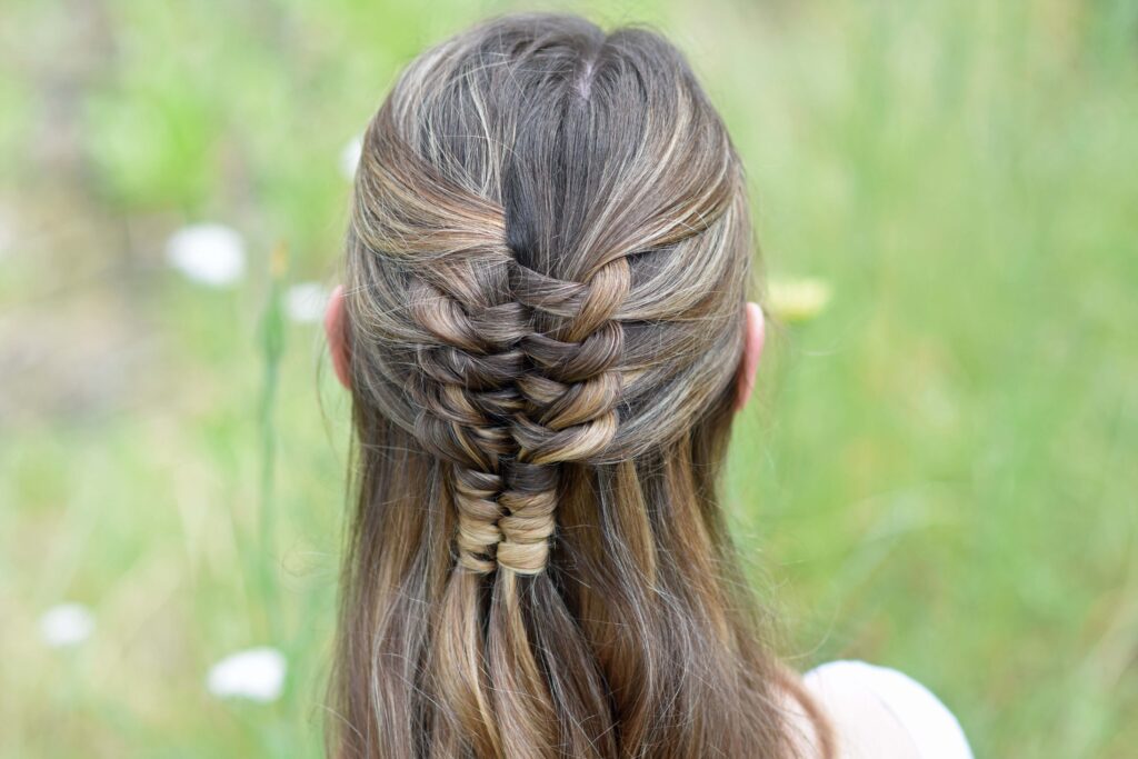 Close up back view of young girl standing in a meadow modeling "Floating Infinity Braid" hairstyle