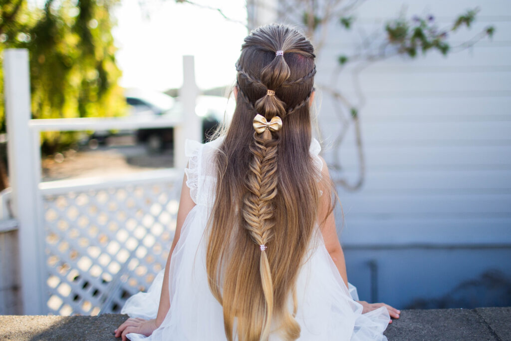 Back view a cute little girl with long hair standing outside modeling "Micro Bubble Braid" hairstyle