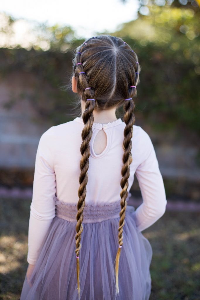 Back view of little girl standing outside in her tutu modeling "Banded Twist Braid" hairstyle