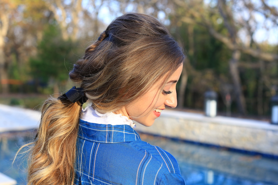 Side view of girl standing outside wearing a blue shirt modeling "Fishtail Ponytail" hairstyle 