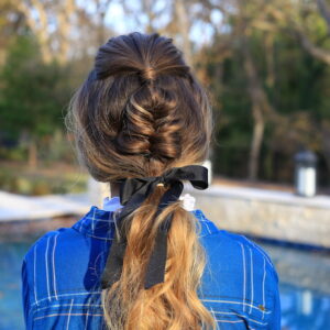Back view of girl standing outside wearing a blue shirt modeling "Fishtail Ponytail" hairstyle