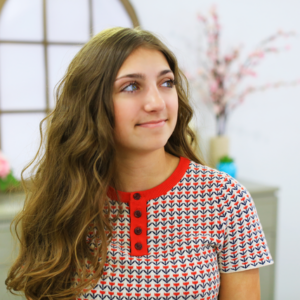 Young girl with curly hair sitting in her room smiling