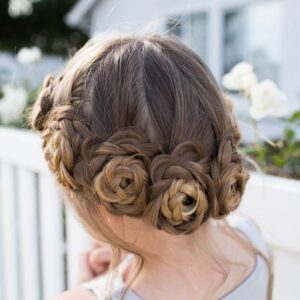 Back view of young girl standing outside in front of white flowers modeling "Flower Crown Braid" hairstyle