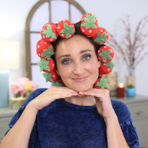 Portrait of woman sitting indoors wearing 'Strawberry Foam Curlers' product in her hair