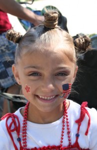 Young girl smiling outside in 4th Of July attire and stamps on her face