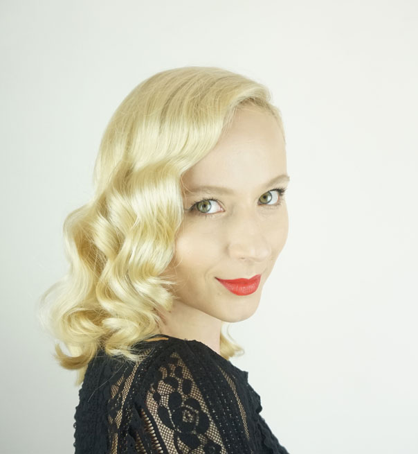 Blonde woman wearing a black shirt in front of a white background wearing red lipstick