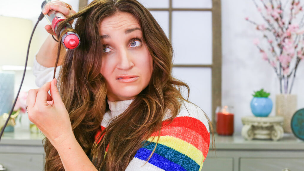 A woman using a curling iron to style her hair.