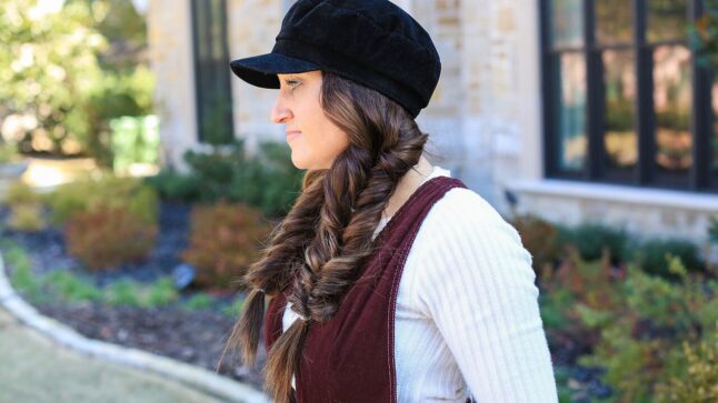 Profile view of Mindy Mcknight standing outdoors modeling the "Fluffy Faux Fishtail" braids