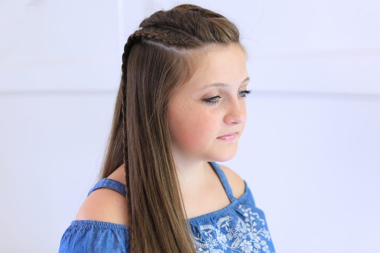 Side view of girl with blue shirt standing indoors modeling the "Dutch Lace Braid Combo" hairstyle