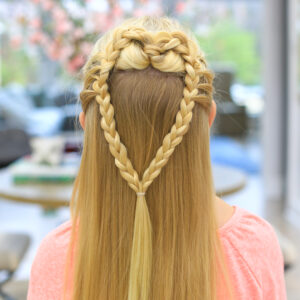 back view of a girl with long blonde hair standing indoors modeling the "Mermaid Hair Braid" hairstyle
