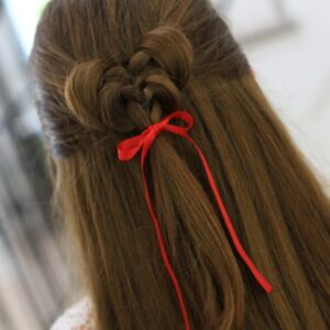 Back view of girl standing indoors wearing a red ribbon in her hair modeling the "Butterfly Tieback" hairstyle