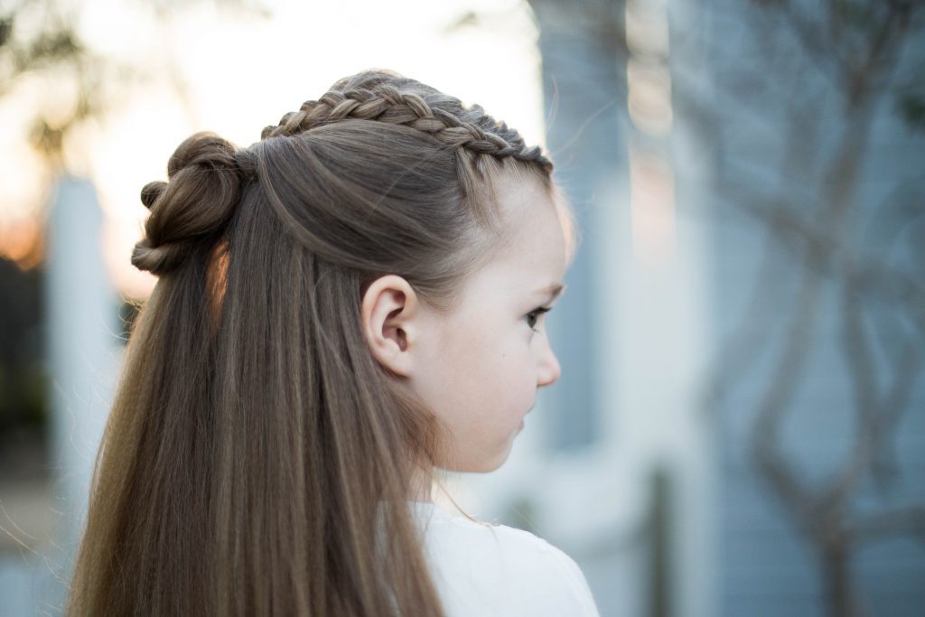 Profile of a young girl outside modeling cute "Braided Bun Combo" hairstyle