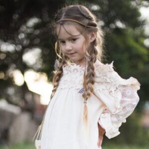 Girl with hands on her hips outside wearing a boho-inspired headband modeling "Boho Side Braids" hairstyle