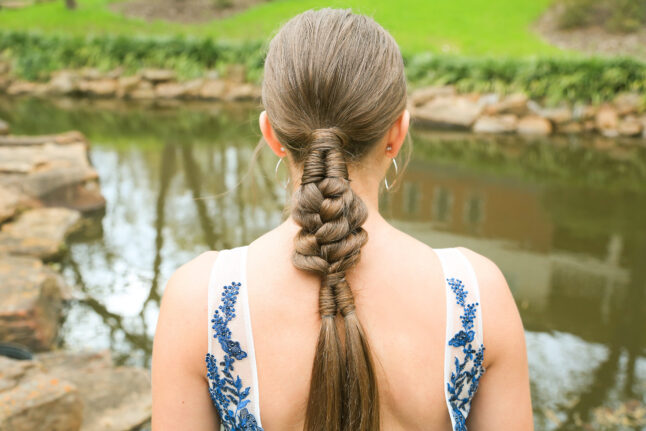 back view of burnette girl with standing by pond with low infinity braid combo hairstyle.