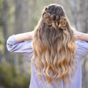 Back view of girl standing outside in the wooded area modeling the "Lace Pull-Thru Rosette Bun" hairstyle