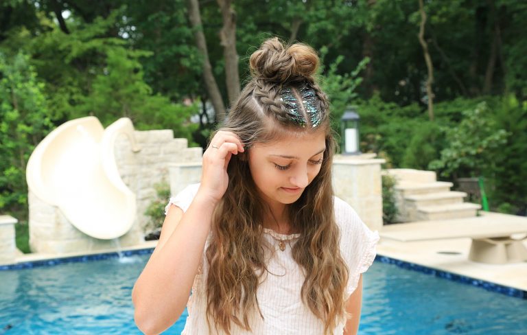 Girl standing by the pool with glitter in her hair modeling Double Dutchbacks into a Messy Bun hairstyle.