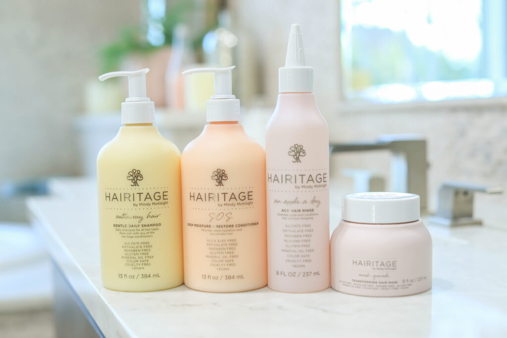 Haircare products sitting on the bathroom counter (left to right) shampoo, conditioner, apple cider vinegar hair rinse, and hair mask