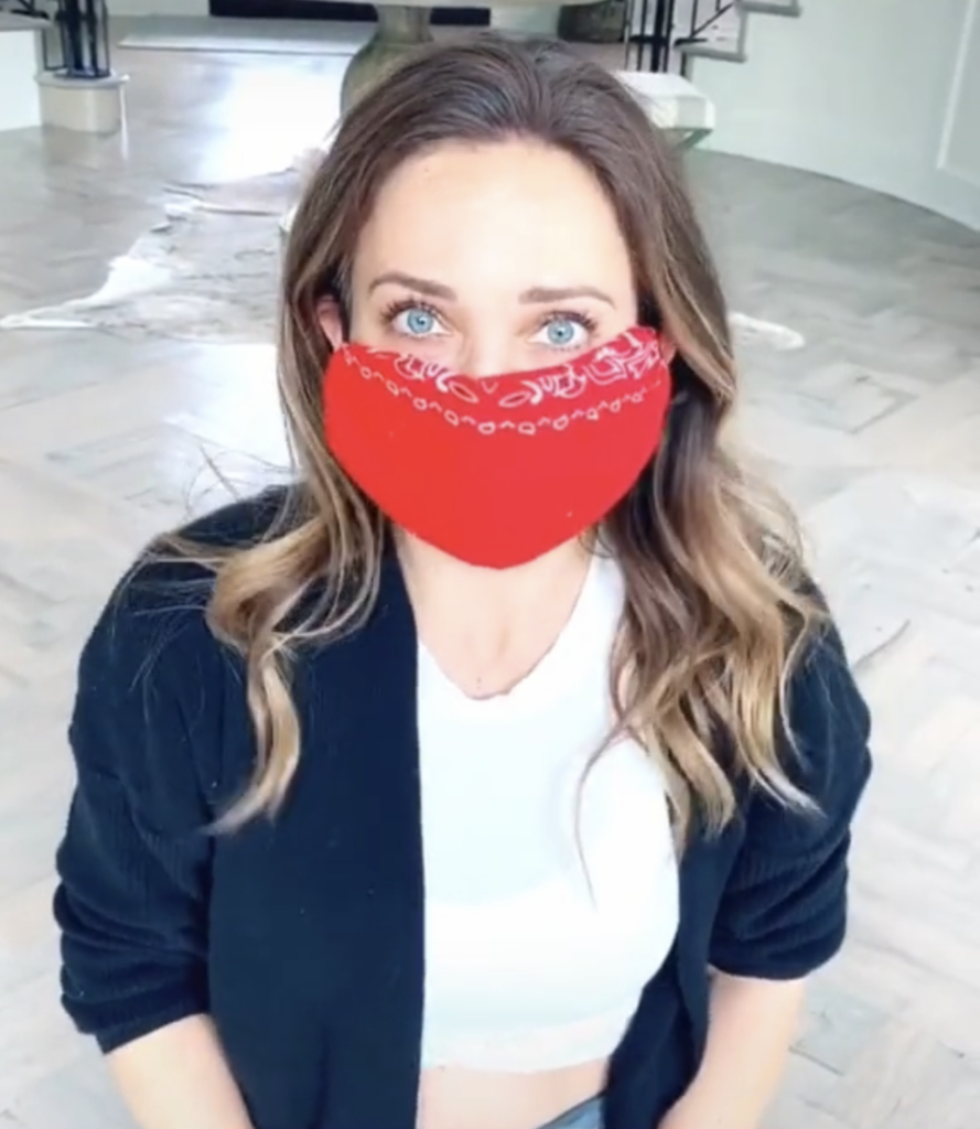 Portait of woman sitting on the floor wearing a red homemade bandana mask